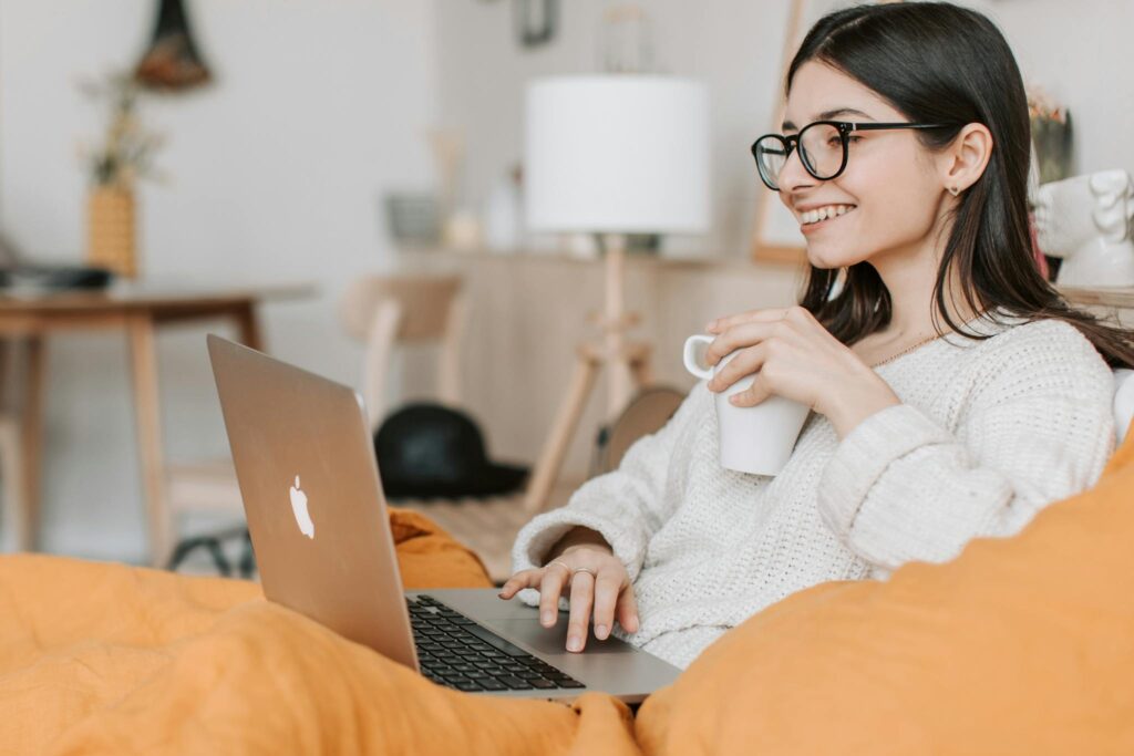 Photo by Vlada Karpovich Woman enjoying a cozy moment with a laptop and coffee in a modern interior setting.